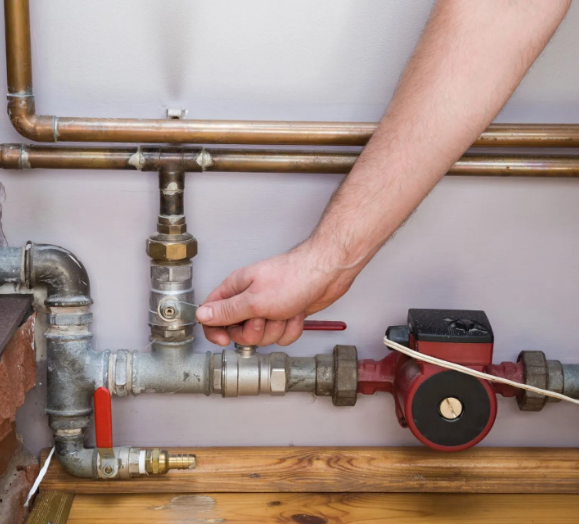 A person is working on the pipes of a water heater.