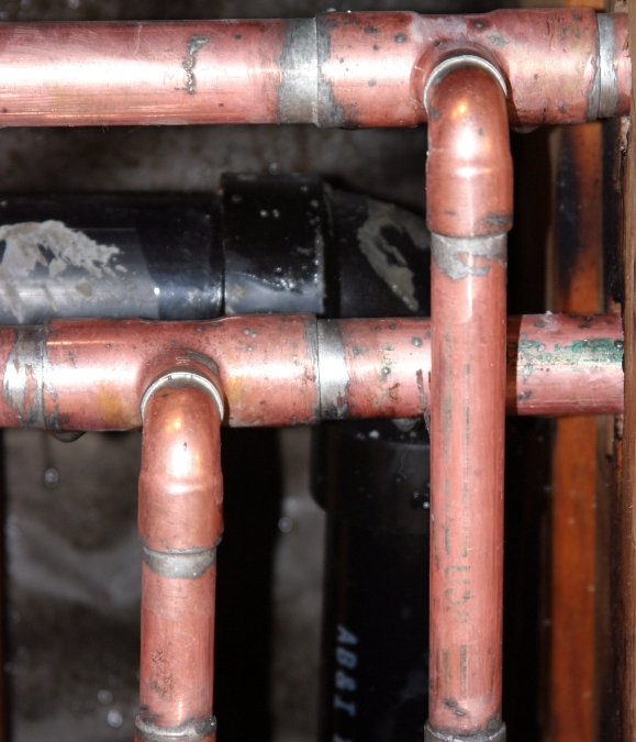 A close up of copper pipes in the middle of a room.